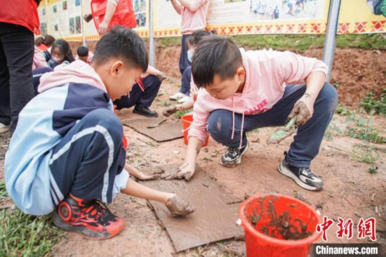 图为小学生往育秧盘上填土。　陈冠言 摄